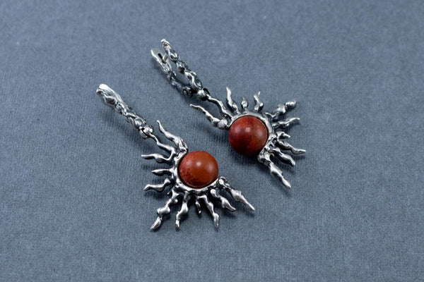 Silver earrings with red stones on a gray background