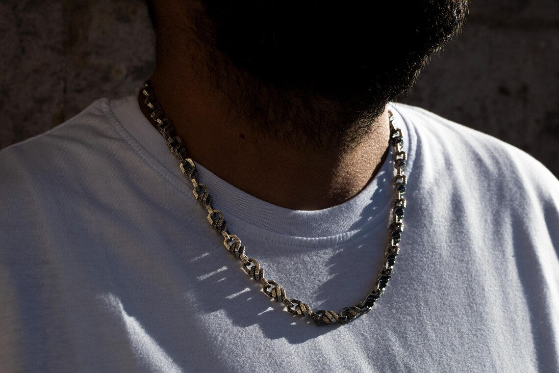 Person wearing a chain necklace on a plain background