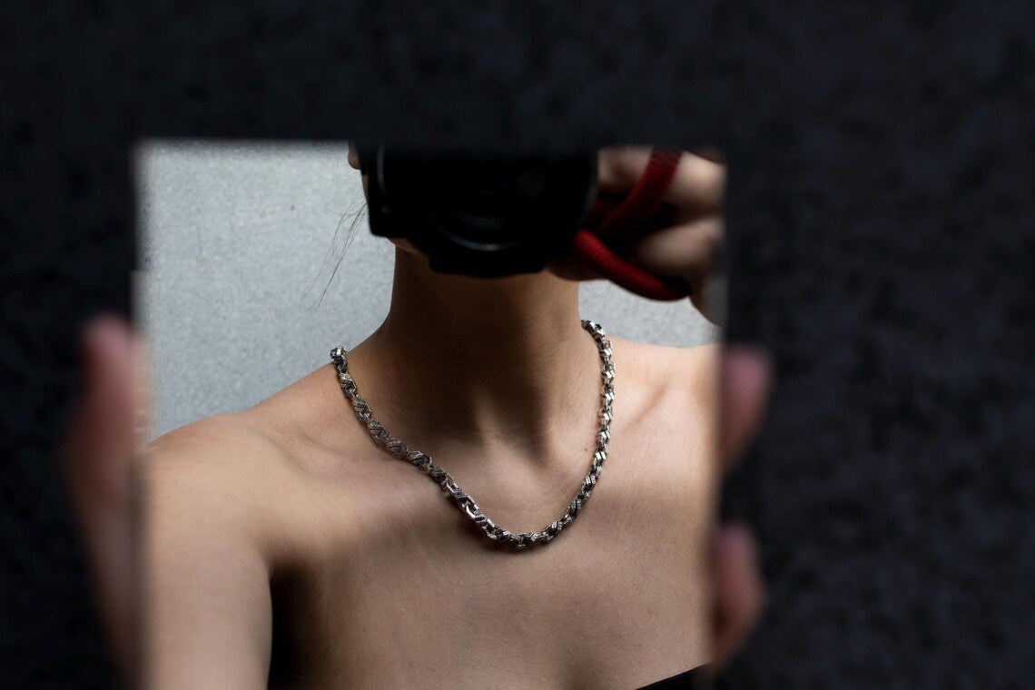 Person wearing a chain necklace with a blurred background
