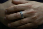 Close-up of a hand wearing a silver ring with intricate design.