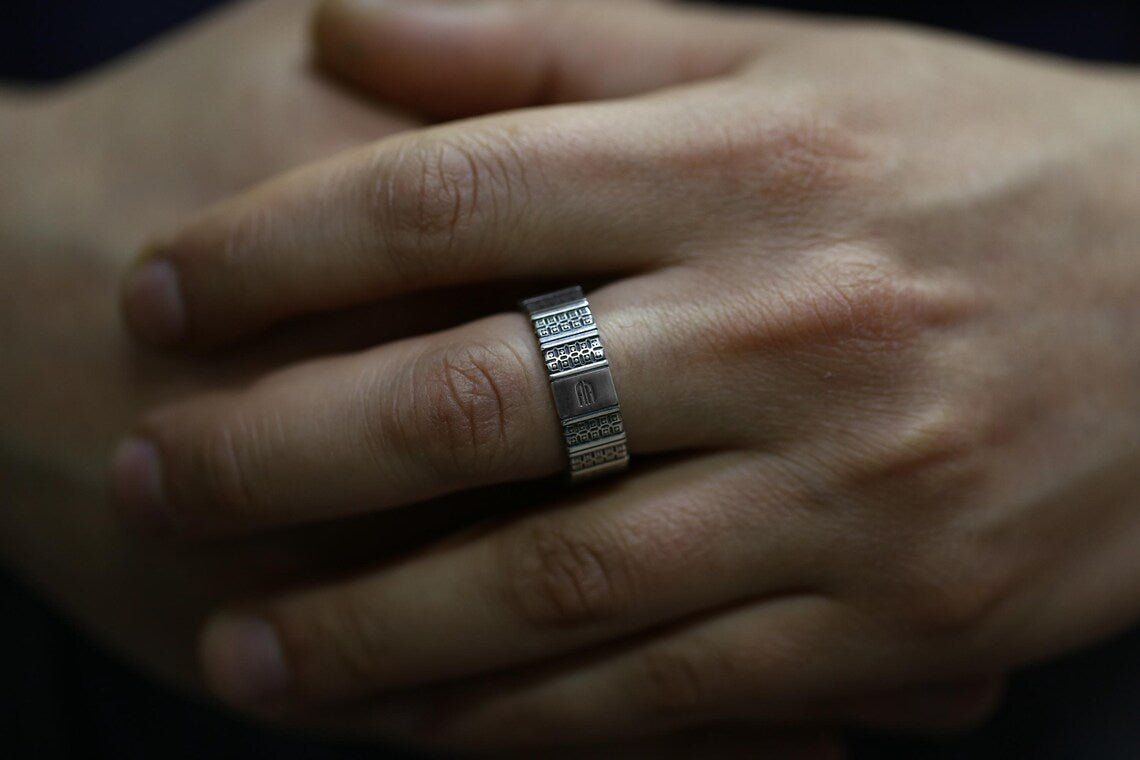 Close-up of a hand wearing a silver ring with intricate design.
