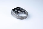 Silver ring with intricate design on a light gray background