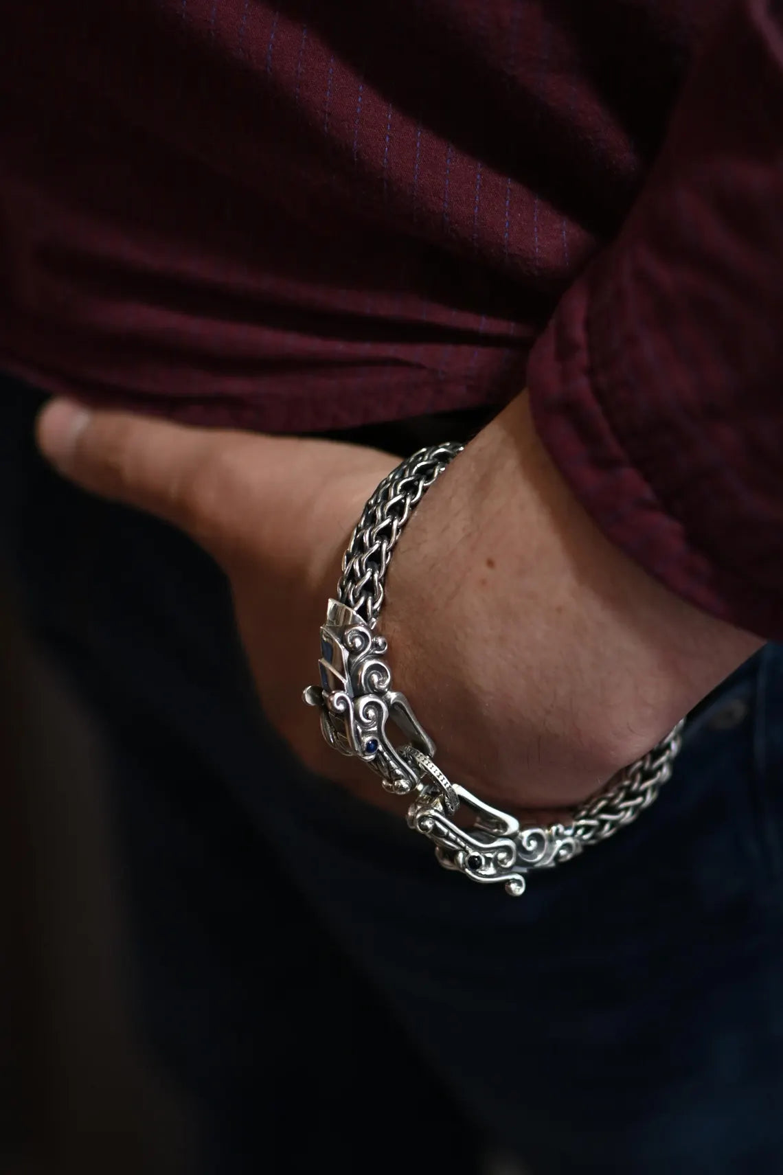 Close-up of a wrist wearing a silver chain bracelet with a dark background