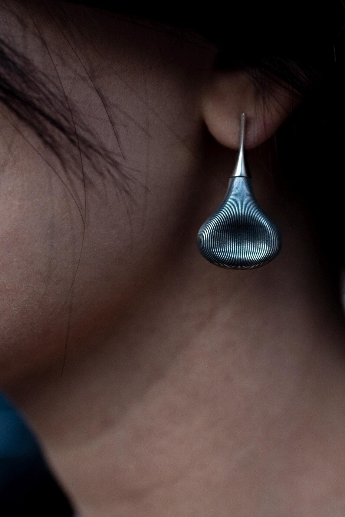 Close-up of a blue earring being worn