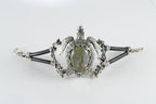 Silver bracelet with a central stone on a white background