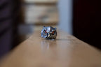 Silver owl-shaped ring on a wooden surface with a blurred background