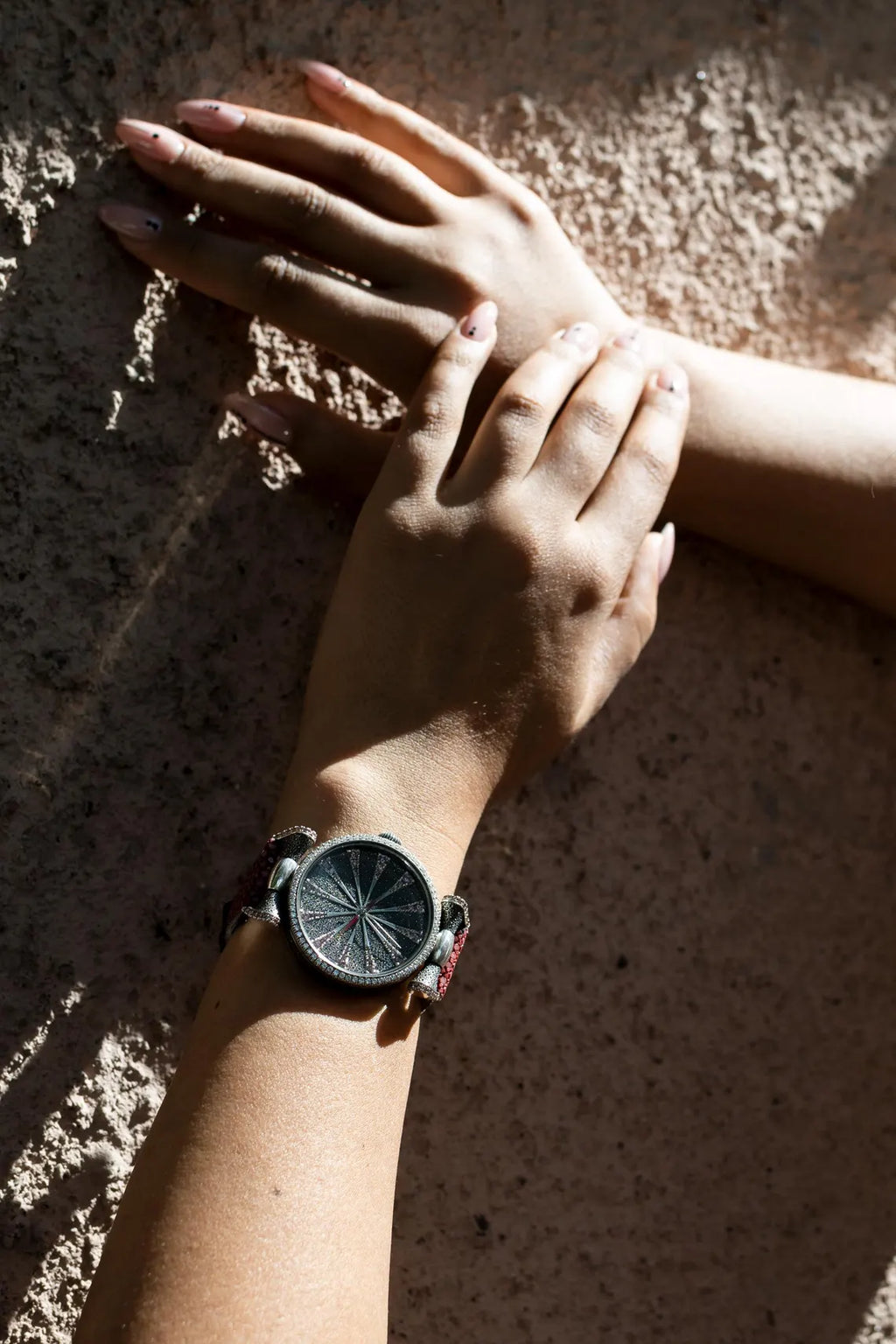 Close-up of hands with a watch on a textured surface
