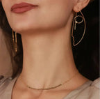 Close-up of a woman wearing gold hoop earrings and a necklace.