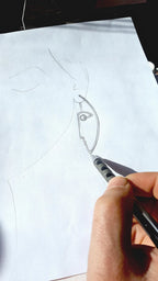 Hand holding a pen over a piece of paper with a design sketch.