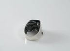 Silver ring with black pattern on a white background