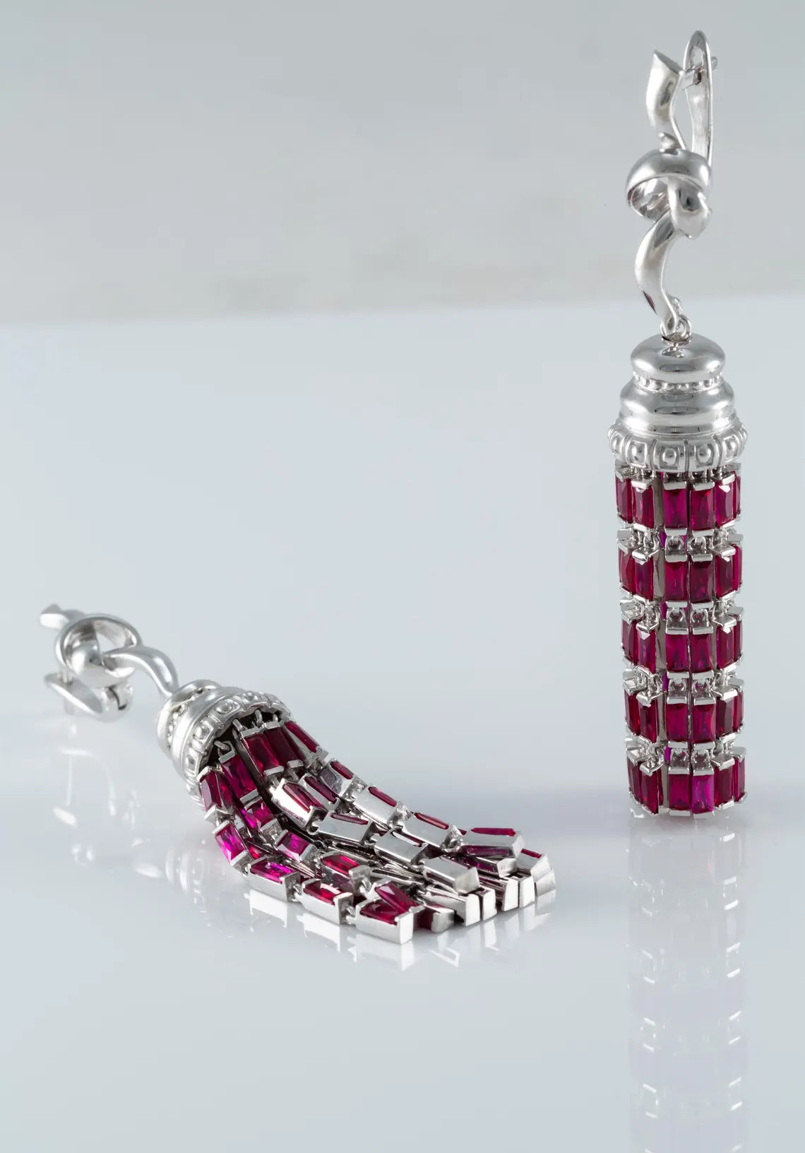 Pair of silver earrings with red gemstones on a white background