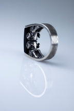 Silver ring with a detailed design on a light gray background