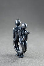 Metallic sculpture of two people embracing on a gray background