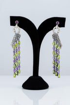 Pair of earrings with wing designs on a black display stand against a white background