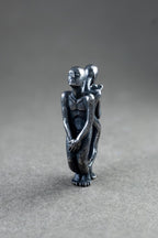 Small metallic sculpture of two figures on a gray background