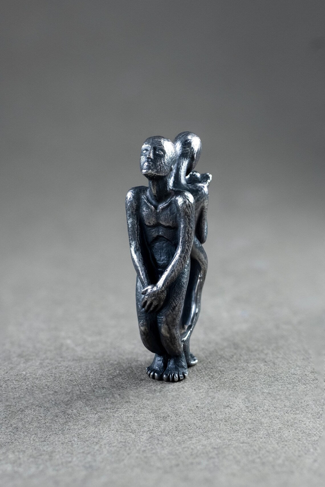 Small metallic sculpture of two figures on a gray background