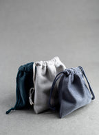Three drawstring bags in blue, gray, and white on a gray background
