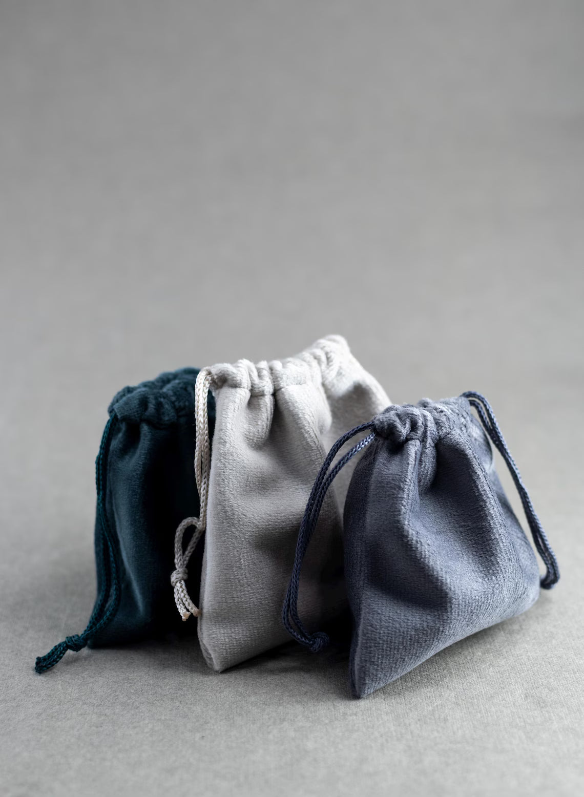 Three drawstring bags in blue, gray, and white on a gray background