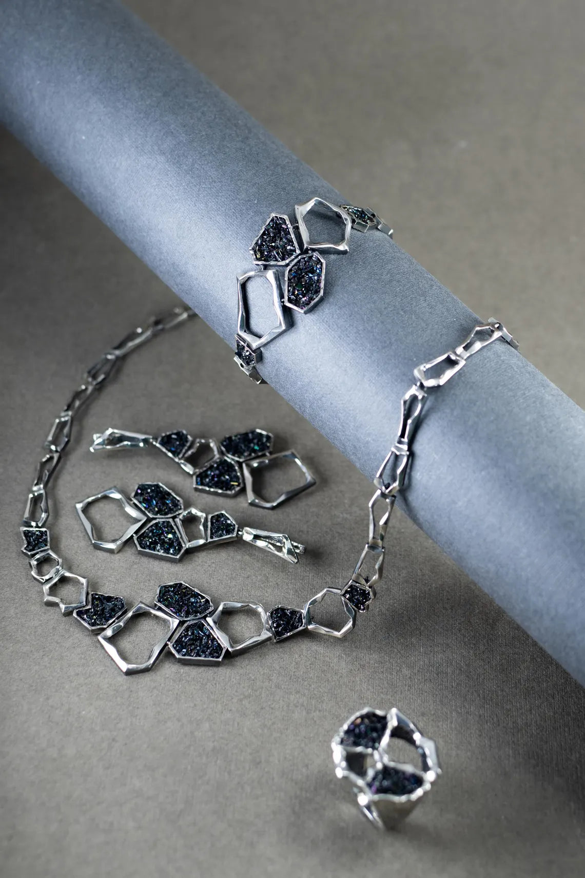 Silver jewelry set with geometric design on a gray surface