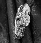 Silver horse head pendant on a dark background