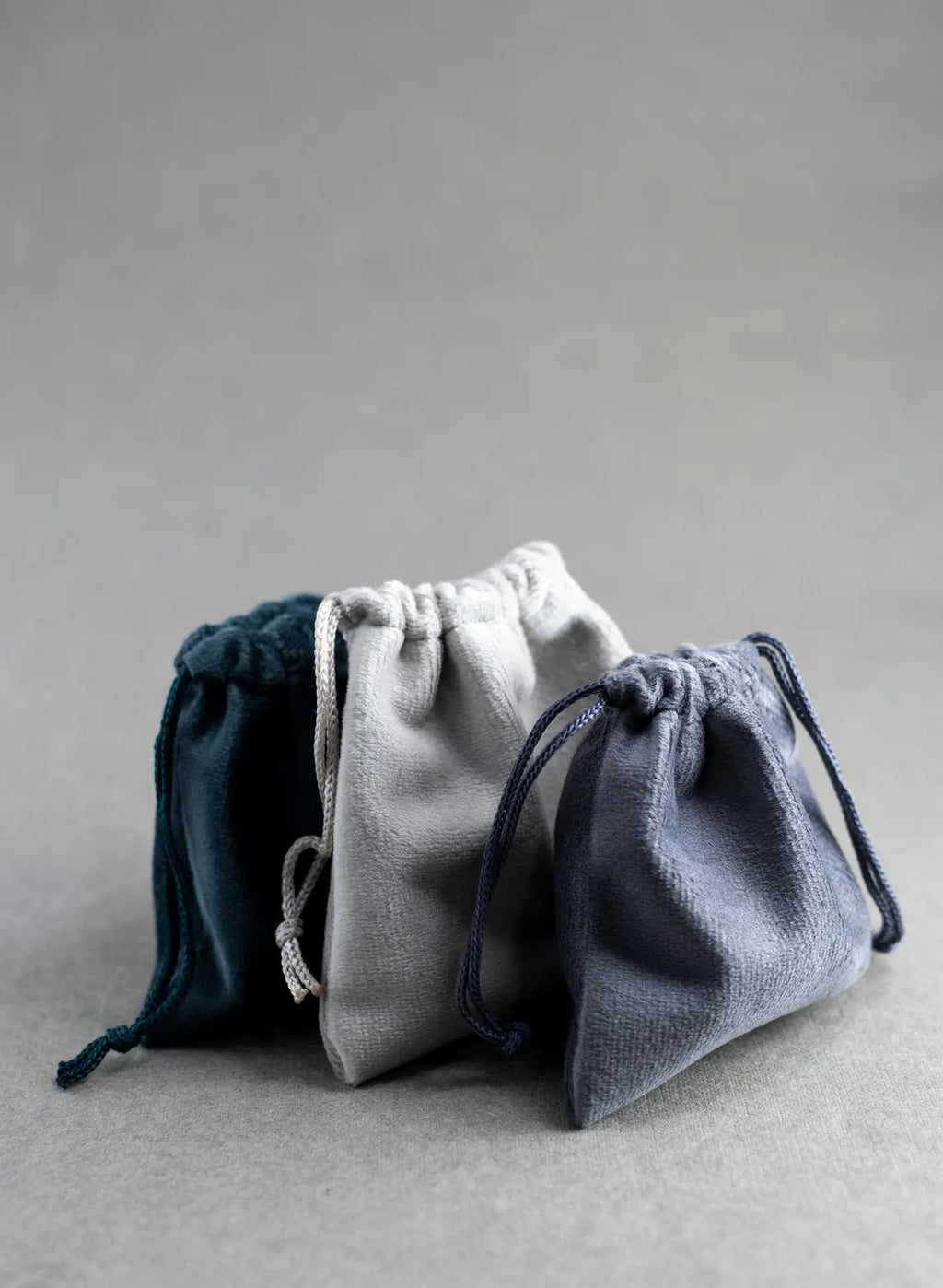 Three drawstring bags in blue, gray, and navy on a gray background