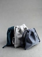 Three drawstring bags in blue, gray, and navy on a gray background