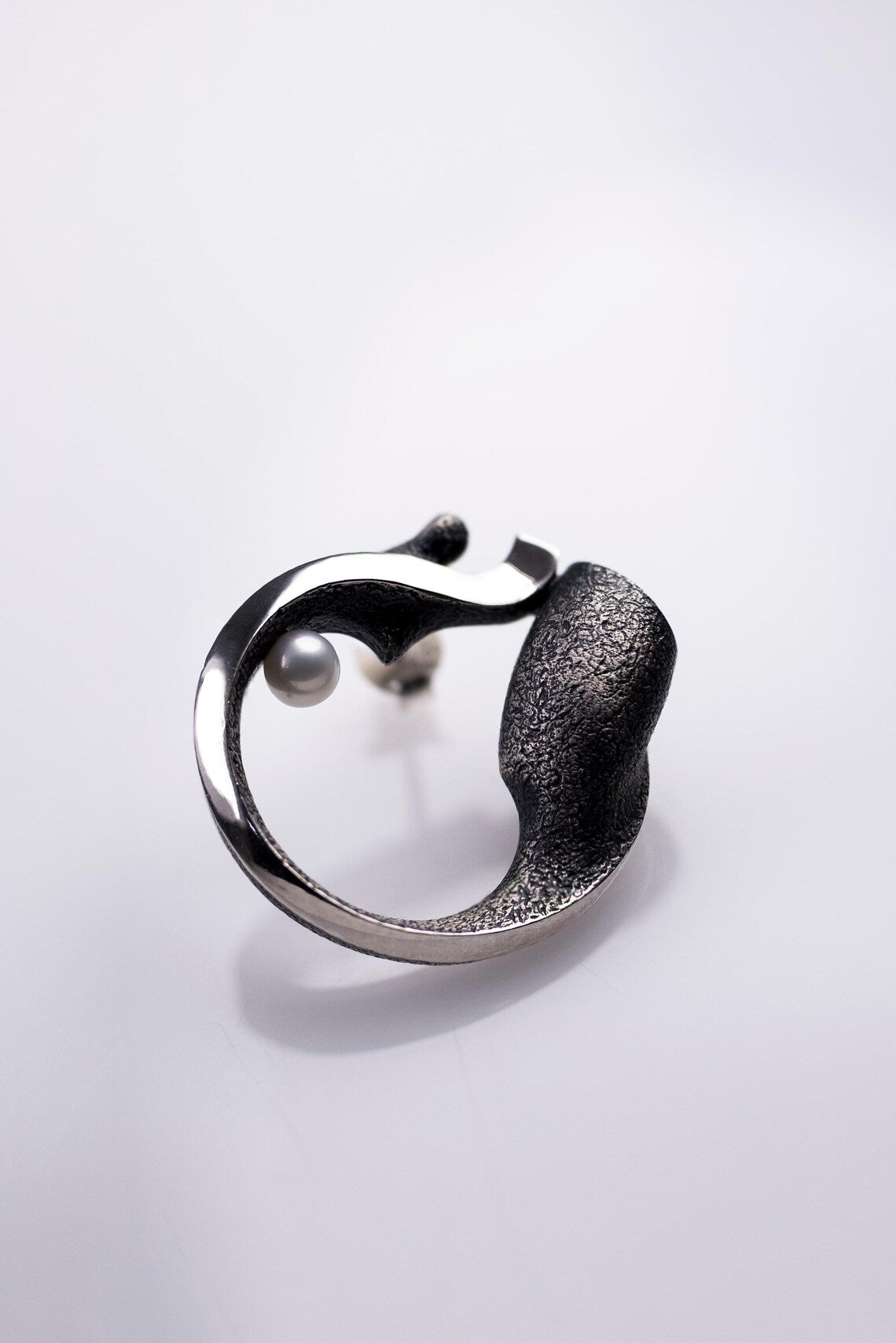 Silver ring with a textured band on a light gray background