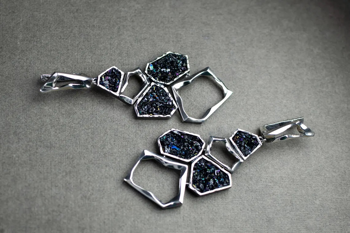 Silver jewelry set with geometric design on a gray background