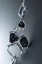 Silver pendant with black gemstones on a textured gray background