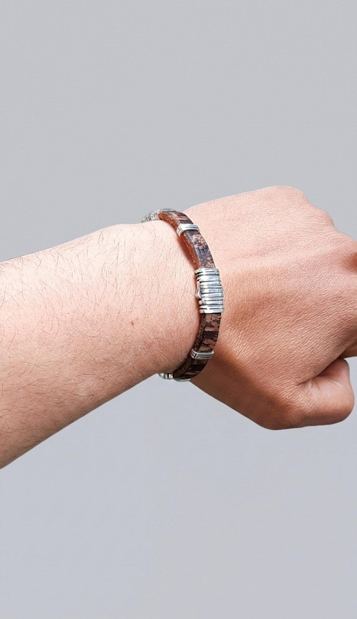 Hand wearing a bracelet on a gray background