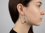 Woman wearing a silver hoop earring with a gray background