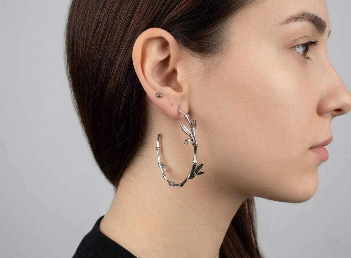 Woman wearing a silver hoop earring with a gray background