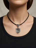 Person wearing a black necklace with a silver pendant on a neutral background