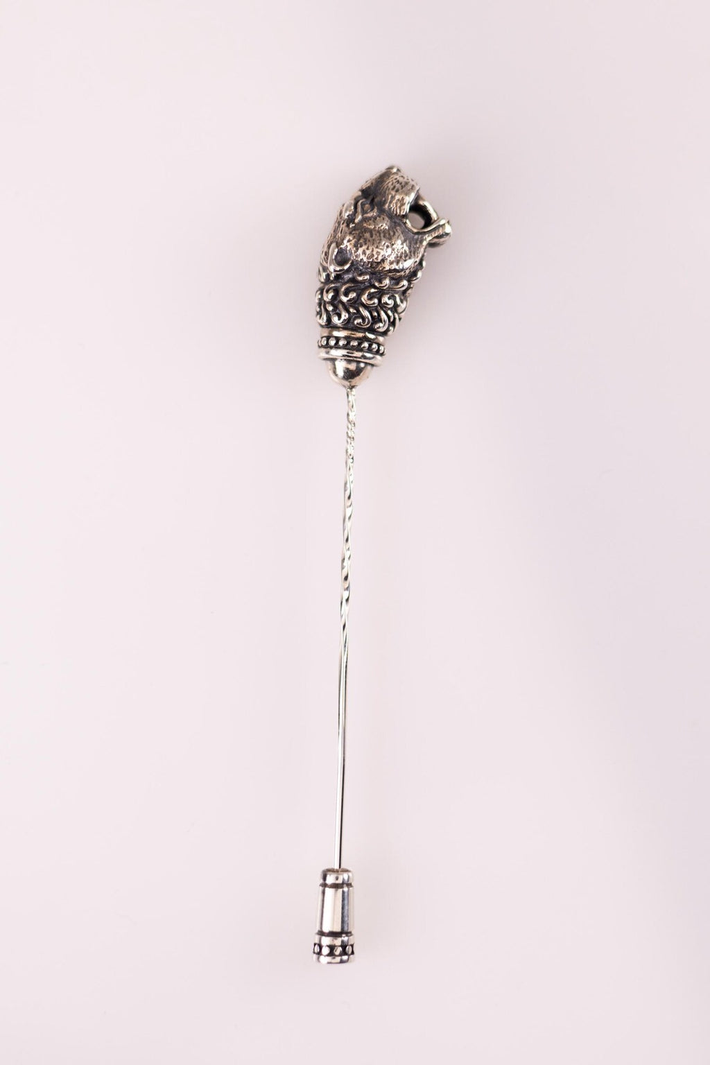 Decorative silver brooch with intricate design on a white background