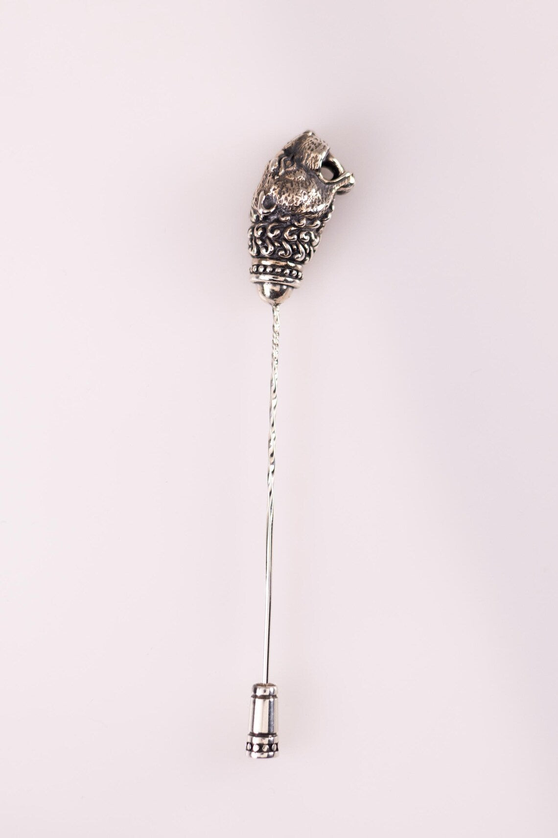 Decorative silver brooch with intricate design on a white background