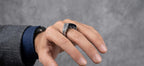 Hand wearing a silver ring on a gray background