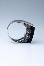 Silver ring with a black stone on a light gray background